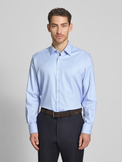 Męski model nosi Regular Fit Business-Hemd mit Kentkragen od ETERNA z bawełny, niebieski, długie rękawy, sportowe mankiety, listwa guzikowa, Ganzkörperansicht von vorne. Długość tyłu w rozmiarze 40: 79 cm, szerokość ramion w rozmiarze 40: 46 cm, długość rękawów w rozmiarze 40: 65 cm.