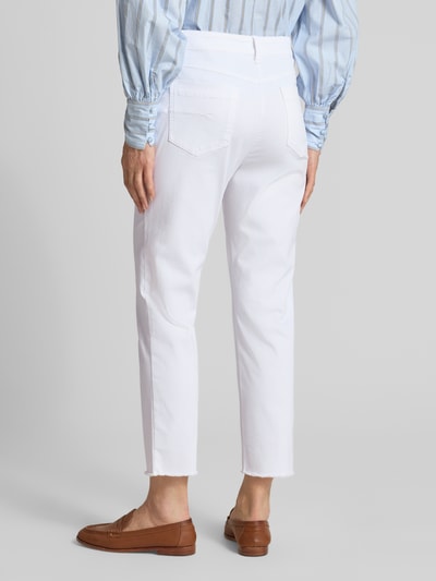 Kobiece modelka nosi chinosy Chino mit Fransensaum von Marc Cain, mieszanka bawełny z dodatkiem streczu, krój slim fit, zapięcie na guzik i zamek błyskawiczny, wpuszczane kieszenie francuskie, frędzle na dole, kieszenie z tyłu, szerokość w rozmiarze 36: 40 cm, długość wewnętrzna nogawki w rozmiarze 36: 67 cm, widok całej sylwetki z tyłu.