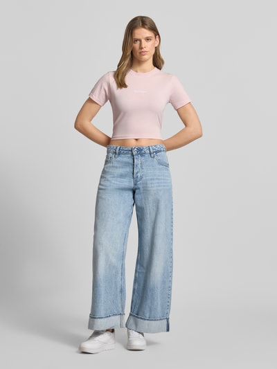 Kobiece modelka nosi Cropped T-Shirt mit Label-Stitching von Pegador z mieszanki bawełny i elastanu, okrągły dekolt, wyhaftowane logo, długość tyłu w rozmiarze S: 41 cm, jasnoróżowy kolor, prosta faktura, całkowity widok z przodu