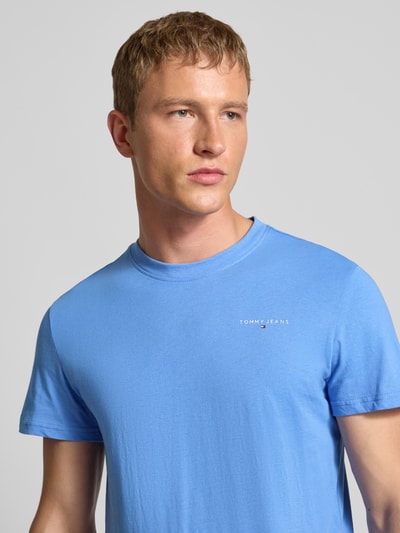 Männermodel trägt Slim Fit T-Shirt aus reiner Baumwolle von Tommy Jeans, Optik: Unifarben, Label-Print, Rundhals, Kurzarm, Nahaufnahme Oberkörper.