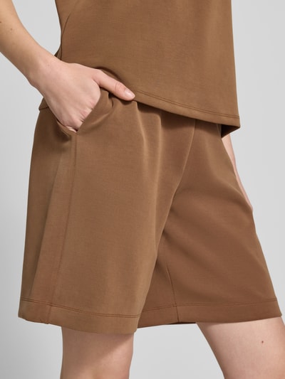 Frauenmodel trägt Top aus Modal-Mix mit Rundhalsausschnitt von Rich & Royal in Braun, glatte Textur, Regular-Fit, Nahaufnahme Oberschenkel.