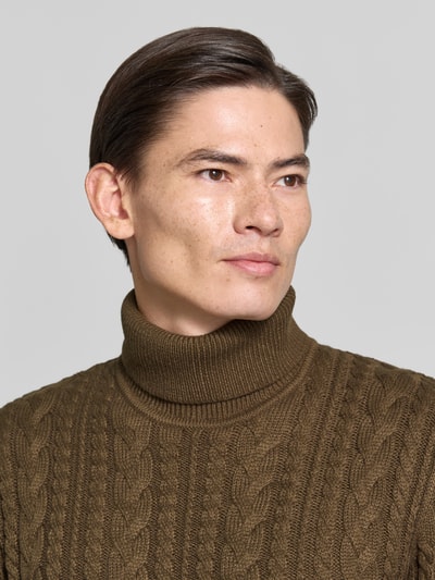 Männermodel trägt Slim Fit Strickpullover mit Baumwoll-Anteil Modell 'Callum' von JACK & JONES, Zopfmuster, gerippter Rollkragen, Nahaufnahme Oberkörper.