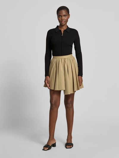 Frauenmodel trägt Slim Fit Jacke aus Viskose-Mix von Victoria Beckham in Schwarz mit Polokragen, Strick-Optik und Reißverschluss, Ganzkörperansicht von vorne.