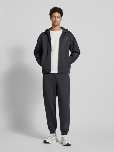Männermodel trägt Sweatpants mit Logo und elastischem Bund von adidas Sportswear, Materiaalmix met katoen, regular fit, logo, elastische band, tunnelkoord, binnenbeenlengte maat M 75 cm, Ganzkörperansicht van voren