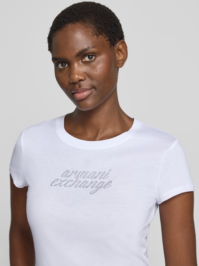 Frauenmodel trägt T-Shirt mit Ziersteinbesatz und Rundhalsausschnitt von Armani Exchange, reine Baumwolle, Slim Fit, weiß, Nahaufnahme Oberkörper.
