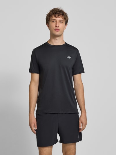 Męski model nosi Funktionsshirt mit Rundhalsausschnitt und Logo od New Balance, kolor czarny, krój regular fit, okrągły dekolt, logo, Długość tyłu w rozmiarze M: 69 cm, całkowity widok z przodu.