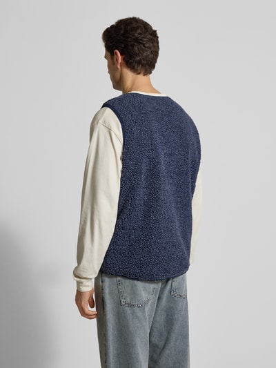 Männermodel trägt Straight Fit Weste mit Logo-Patch Modell 'Hoktown' von American Vintage aus blauem Kunstfell, Ganzkörperansicht Rückansicht.
