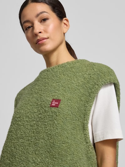 Vrouwenmodel draagt Loose Fit Pullunder Woll-Anteil Modell 'ZOLLY' van American Vintage in olijfgroen, grofgebreide textuur, ronde hals, label-stitching, materiaal met alpacawol, context: dames pullunder, ruglengte 65 cm bij maat XS/S, Nahaufnahme bovenlichaam.