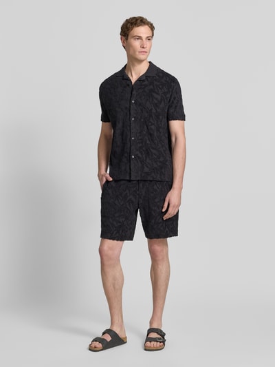 Männermodel trägt Regular Fit Sweatshorts aus reiner Baumwolle von Marc O'Polo mit floralem Allover-Muster, Jersey-Frottee, Ganzkörperansicht von vorne.