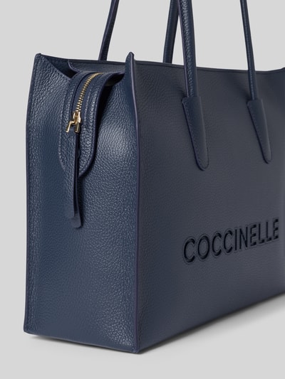 Produktfoto, saszetka Pochette mit Tragehenkeln und Logo Modell 'MYRTHA26' von Coccinelle, główna przegroda z zamkiem błyskawicznym, logo, szerokość w rozmiarze 1: 36 cm, długość w rozmiarze 1: 28 cm, głębokość w rozmiarze 1: 13 cm, długość paska na ramię w rozmiarze 1: 67 cm, struktura o fakturze groszkowej, kolor ciemnoniebieski
