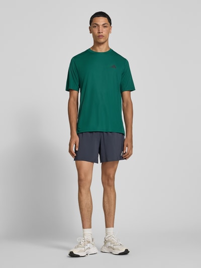 Mężczyznęmodel nosi Regular Fit Sportshorts mit Logo-Print Modell 'Run Ess Shor M' od adidas Training, widok całej sylwetki z przodu.
