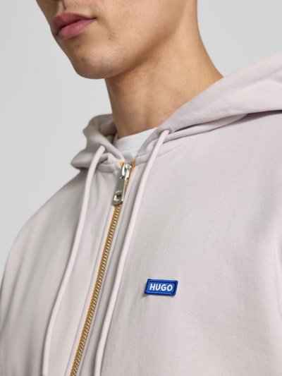 Männermodel trägt Relaxed Fit Sweatjacke aus reiner Baumwolle Modell 'Nadarasi' von HUGO, Optik: Unifarben, Label-Print, Reißverschluss, Materialverarbeitung: Sweat, Nahaufnahme Oberkörper.
