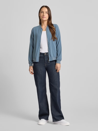 Kobiece model nosi Regular Fit Bomberjacke mit College-Kragen Modell 'COCO' od Vero Moda, niebieska, gładka, długie rękawy, zamek, widok całej sylwetki z przodu.