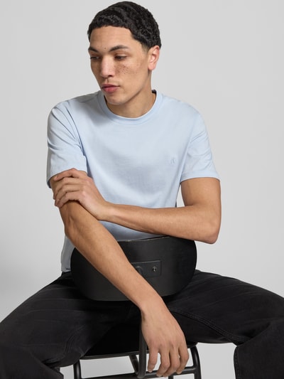 Männermodel trägt Regular Fit T-Shirt mit Logo-Detail von Replay in Hellblau aus reiner Baumwolle, Rundhalsausschnitt, Nahaufnahme Oberkörper.