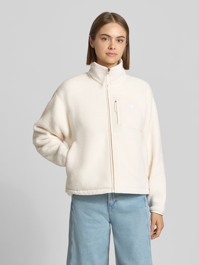 Kobiece modelka nosi kurtka z polaru o kroju regular fit Model 'YUMIORI' od The North Face, stójka, wyhaftowane logo, zamek błyskawiczny, jasny kolor, gładka faktura, Długość tyłu w rozmiarze S: 58 cm, Szerokość ramion w rozmiarze S: 52 cm, Szerokość w rozmiarze S: 58 cm, Długość rękawów w rozmiarze S: 57 cm, widok całej sylwetki z przodu.