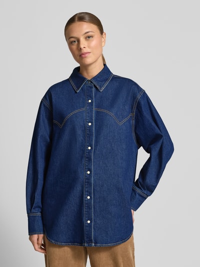 Frauenmodel trägt Relaxed Fit Jeansbluse mit Knopfleiste von Scotch & Soda, mieszanka bawełny z dodatkiem streczu, kołnierzyk koszulowy, długość tyłu 56 cm, długość rękawów 73 cm, kolor ciemnoniebieski, gładka tekstura, listwa guzikowa, Ganzkörperansicht von vorne.