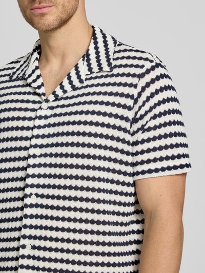 Männermodel trägt Relaxed Fit Poloshirt aus Baumwoll-Mix Modell 'DYLAN' von SELECTED HOMME, Optik:Allover-Muster, Nahaufnahme Oberkörper.