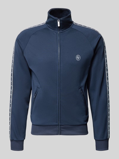 Produktfoto, Trainingsjacke mit aufgesetztem Band auf Raglanärmeln von REVIEW in Dunkelblau mit Logo, Stehkragen und Reißverschlusstaschen.