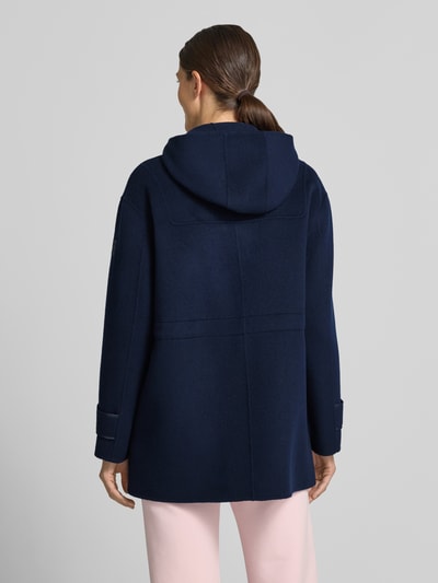 Vrouwenmodel draagt Regular Fit lange wollen jas uit zuiver wol van Marc Cain in donkerblauw met opstaande kraag, tunnelkoord, opgestikte steekzakken en doorlopende knoopsluiting; Ruglengte maat 36: 78 cm, schouderbreedte 46 cm, borstwijdte 41 cm, mouwlengte 56 cm; geheel van achteren.