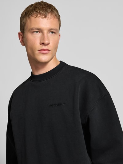 Männermodel draagt Oversized sweatshirt met labelstitching van Pegador in zwart katoenmix met ribboorden en ronde hals, Nahaufnahme Oberkörper.