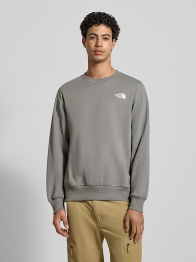Mannelijk model draagt Sweatshirt met Label-Print van The North Face, grijs, katoen, losse pasvorm, geribde randen, vooraanzicht volledige lichaamsopname.