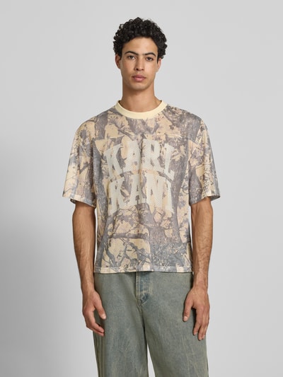 Männermodel trägt T-Shirt aus Mesh mit Logo von KARL KANI in Beige- und Brauntönen, Regular Fit, Rundhalsausschnitt, Ganzkörperansicht von vorne.