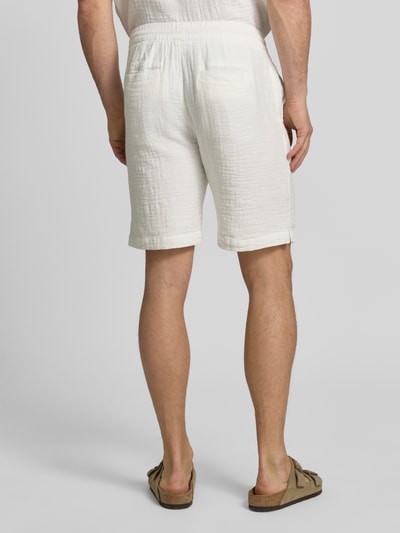 Männermodel trägt Shorts mit Eingrifftaschen und elastischem Bund von Lindbergh aus Reine Baumwolle im Loose-Fit, Ganzkörperansicht Rückansicht.