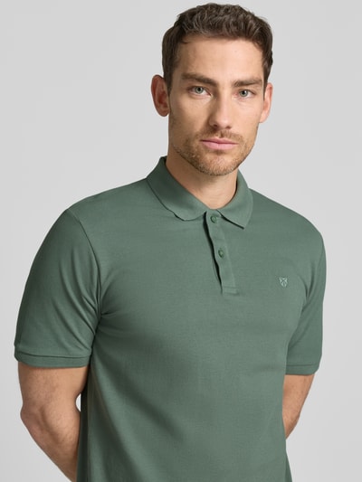 Męski model nosi Slim Fit Poloshirt mit Stitching von Jack & Jones Premium z bawełny, krój slim fit, haft, listwa guzikowa, długość tyłu w rozmiarze M 70 cm, kolor zielony, prosta tekstura, widok na górną część ciała z przodu.