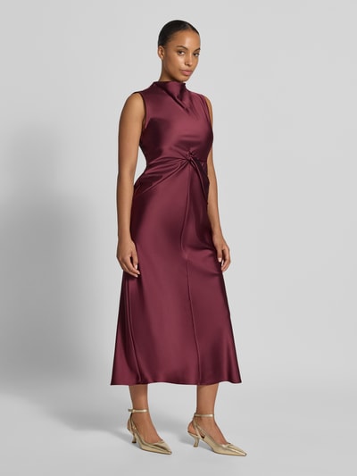 Frauenmodel trägt Cocktailkleid aus Satin mit Raffungen von Rinascimento in Bordeaux, tailliert, ärmellos, Midilänge, Ganzkörperansicht von vorne.