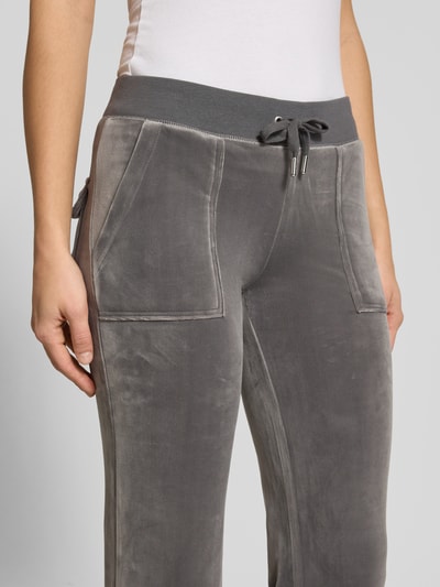 Frauenmodel trägt Low Rise Sweatpants mit elastischem Bund Modell 'LAYLA' von Juicy Couture aus grauem Baumwoll-Mix mit Stretch-Anteil, Flared-Cut und Eingrifftaschen, Nahaufnahme Oberkörper