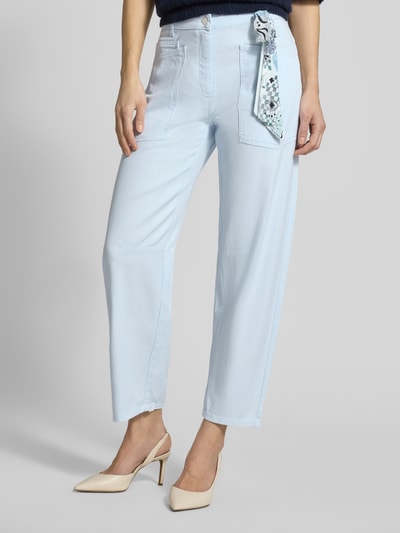 Vrouwenmodel draagt Relaxed Fit Jeans aus Lyocell-Mix van Cambio in lichtblauw met geknoopte doek, verkorte pasvorm, vooraanzicht, context: elastische lyocell-katoenmix, knoop- en ritssluiting, steek- en achterzakken, riemlussen.