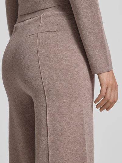 Frauenmodel trägt Stoffhose mit Ziernähten von Christian Berg Woman aus Viskose-Mix in Beige mit angedeuteten Gesäßtaschen, Nahaufnahme Rückansicht.