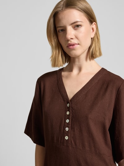 Frauenmodel trägt knielanges Kleid aus Leinen-Viskose-Mix Modell 'Lava' von FREE/QUENT in Dunkelbraun mit V-Ausschnitt, Knopfleiste, Nahaufnahme Oberkörper. Kontext: Damen Kleid, A-Linie, Rückenlänge Größe S: 96 cm, Brustweite: 43 cm, Ärmellänge: 29 cm.
