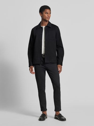 Männermodel trägt Slim Fit Hemdjacke mit Viskose-Anteil von Lindbergh in Schwarz, Umlegekragen, Knopfleiste, Ganzkörperansicht von vorne