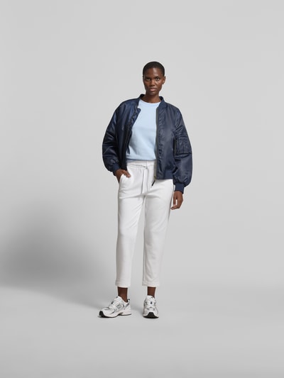 Frauenmodel trägt Sweatpants aus Baumwoll-Mix von Juvia in Weiß mit elastischem Bund und Tunnelzug, Eingrifftaschen, schmal zulaufendem Bein, elastischen Abschlüssen, Material: elastischer Baumwoll-Modal-Mix, Innenbeinlänge 42 cm, Bundweite 67 cm, Ganzkörperansicht von vorne.