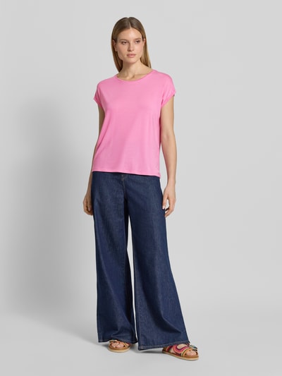 Frauenmodel trägt Damen T-Shirt von Vero Moda, Modell 'AVA', Optik: Unifarben, Passform: Relaxed-Fit, Rundhals-Ausschnitt, Ärmelform: Kurzarm, Ärmelabschluss: Umschlag, Material: Lyocell-Mix, zartes Rosa, glatte Textur, kombiniert mit dunkler Wide-Leg-Jeans, Ganzkörperansicht von vorne.