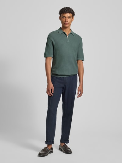 Męski model nosi Regular Fit Poloshirt aus reiner Bio-Baumwolle Modell 'CRAN' od SELECTED HOMME w strukturowanej dzianinie, zielony, z krótkim rękawem, polokołnierzykiem i krótkim zamkiem, widok całej sylwetki z przodu.