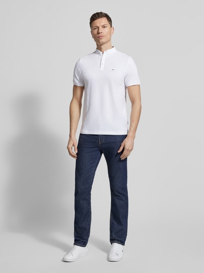 Męski model nosi Regular Fit Poloshirt mit Stehkragen von HECHTER PARIS z bawełny, stójka, listwa guzikowa, wyhaftowane logo, długość tyłu w rozmiarze M: 67 cm, widok całej sylwetki z przodu.