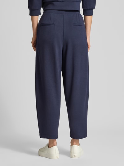 Frauenmodel trägt Sweatpants mit elastischem Bund von Rich & Royal in Dunkelblau, lockerer Schnitt, Gesäßtaschen, Ganzkörperansicht Rückansicht.