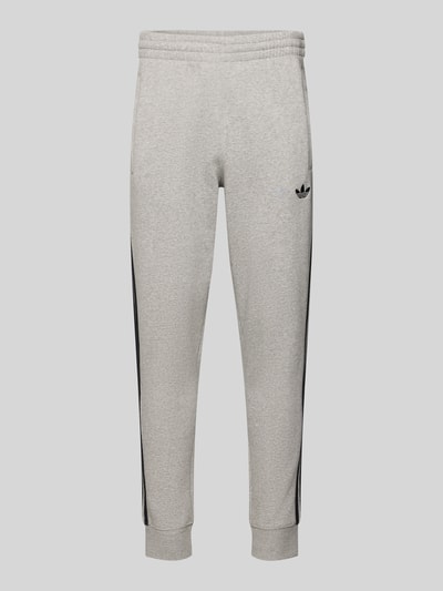 Produktfoto, Sweatpants mit elastischem Bund von adidas Originals aus Katoenmix, los model, labelstitching, steekzakken, binnenbeenlengte maat M 75 cm, melangegrijs met zwarte details