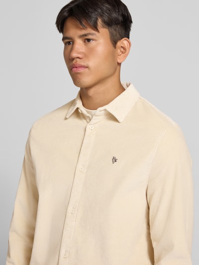 Männermodel trägt Slim Fit Cordhemd aus Baumwoll-Mix von REVIEW in Beige mit Ripp-Optik und Logo-Prägung, Nahaufnahme Oberkörper.
