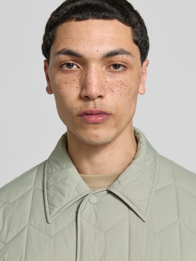 Männermodel trägt Regular Fit Jacke in Stepp-Optik von MAISON KITSUNÉ in hellem Grün, mit Umlegekragen und Knopfleiste, Nahaufnahme Oberkörper. Rückenlänge bei Größe M: 75 cm, Schulterbreite: 48 cm, Ärmellänge: 62 cm, Pattentaschen.