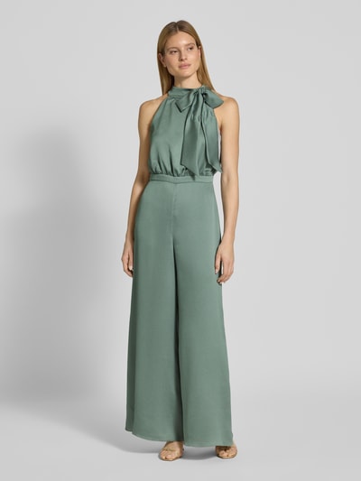 Frauenmodel trägt Jumpsuit mit Schleifen-Detail von SWING in Salbeigrün, Regular-Fit, Neckholder, glatte Textur, Ganzkörperansicht von vorne, Rückenlänge bei Größe 36: 40 cm, Brustweite: 36 cm, Gesamtlänge: 152 cm, Innenbeinlänge: 83 cm, Rückseitiger Reißverschluss.