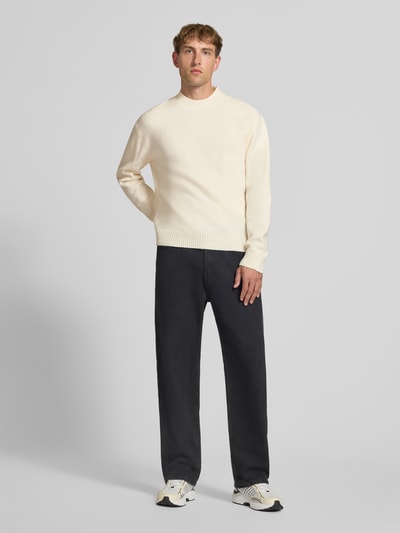 Männermodel trägt Relaxed Fit Strickpullover aus Material-Mix mit Baumwoll-Anteil von REVIEW, helle Farbe, elastische Abschlüsse, Ganzkörperansicht von vorne.