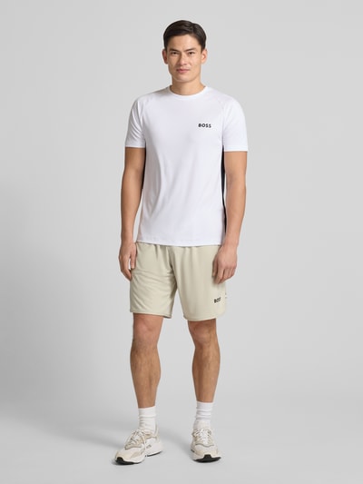 Männermodel trägt Slim Fit T-Shirt mit Label Print Modell 'TOP SPIN CB' von BOSS Green, Optik: Unifarben, Ganzkörperansicht von vorne.