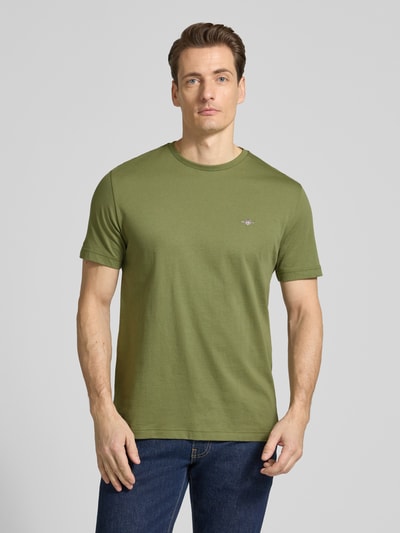 Männermodel trägt Regular Fit T-Shirt mit Logo-Stitching von Gant in Grün, reine Baumwolle, Rundhalsausschnitt, Ganzkörperansicht von vorne
