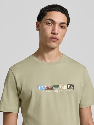 Männermodel trägt T-Shirt aus Bio-Baumwolle Modell 'NANTUCKET' von Jack & Jones in Beige mit Label-Print, Nahaufnahme Oberkörper.