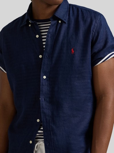 Mannenmodel draagt Regular Fit Leinenhemd met Button-Down-Kragen van Polo Ralph Lauren, look: effen kleuren, regular fit, button-downkraag, doorlopende knoopsluiting, gestikt logo, korte mouw, licht afgeronde rompzoom, materiaal: puur linnen, detailopname bovenlichaam.