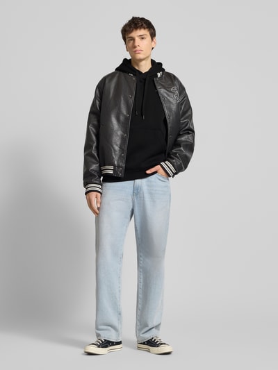 Männermodel trägt Hoodie mit Kapuze von G-Star Raw in Schwarz mit Label-Print, Känguru-Tasche, Baumwoll-Mix, Lockerer-Schnitt, Ganzkörperansicht von vorne.