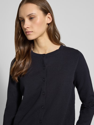 Vrouwenmodel draagt Strick-Cardigan aus Viskose-Mix mit lange mouwen van Review, regular fit, knoopsluiting, geborduurd logo, ribboordjes, zwarte kleur, Nahaufnahme bovenlichaam.
